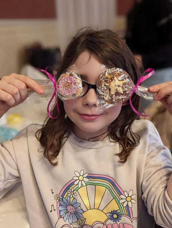 Girl holding up two decorated chocolates at a family class
