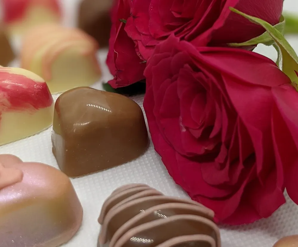 Handmade chocolate hearts beside red roses