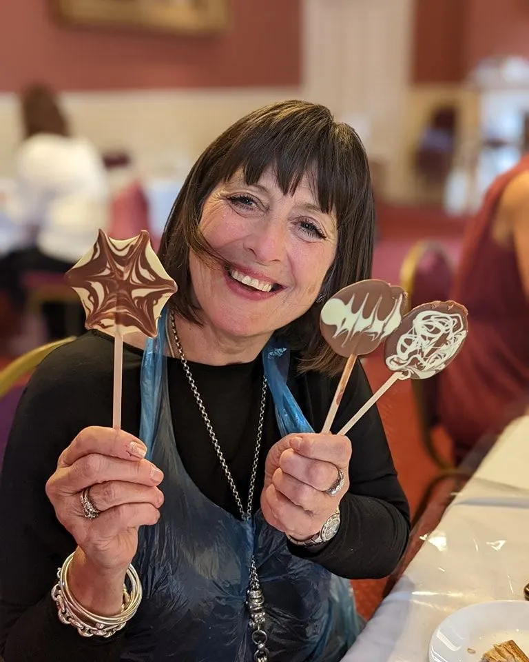 Smiling chocolatier holding two chocolate lollipops